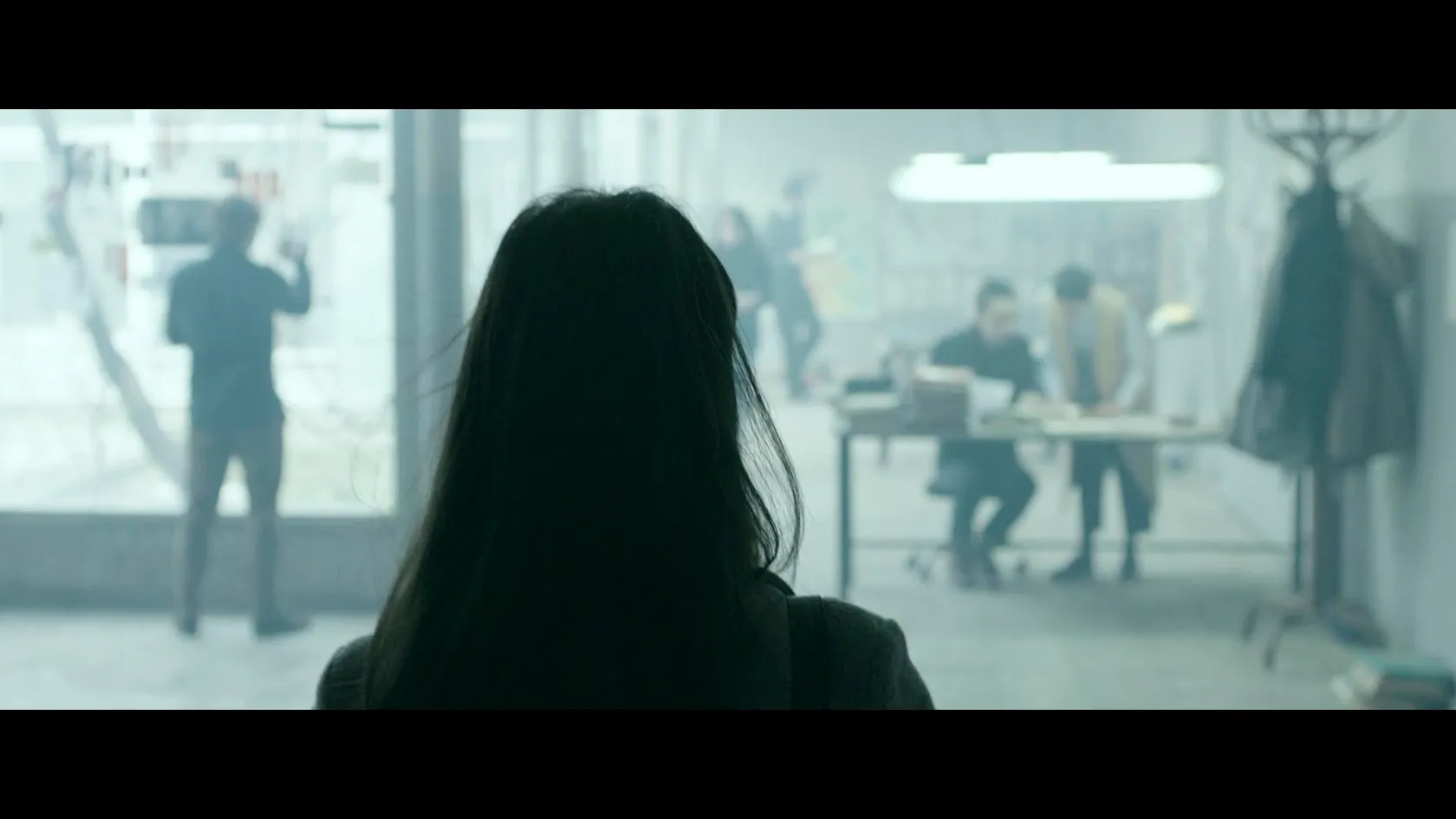 Cinema portfolio by Andrei Kovalev: a silhouetted figure looks into an office where two people work at a cluttered desk.