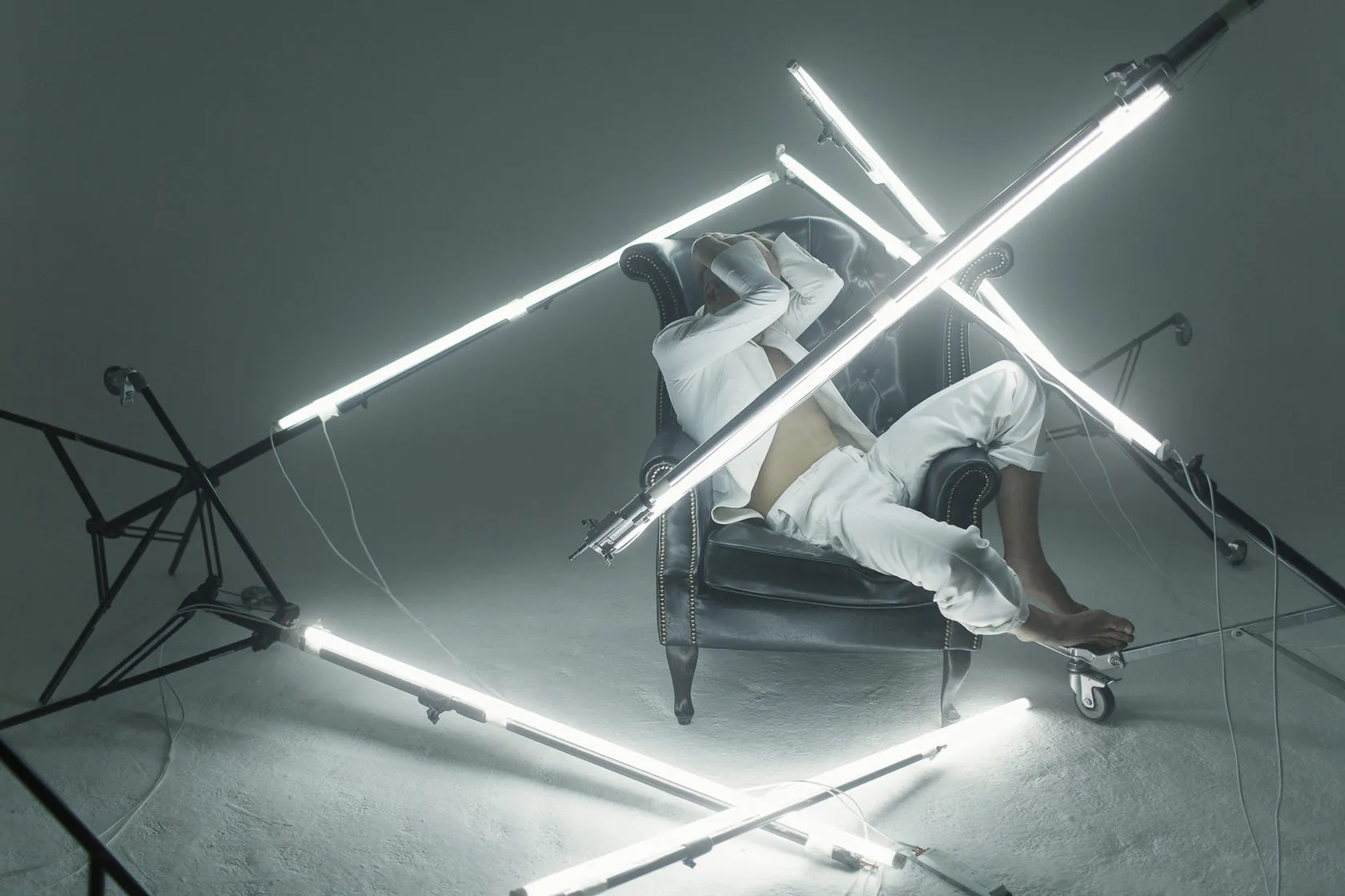 Pavel Ruminov lies across an armchair among crossed fluorescent tubes.
