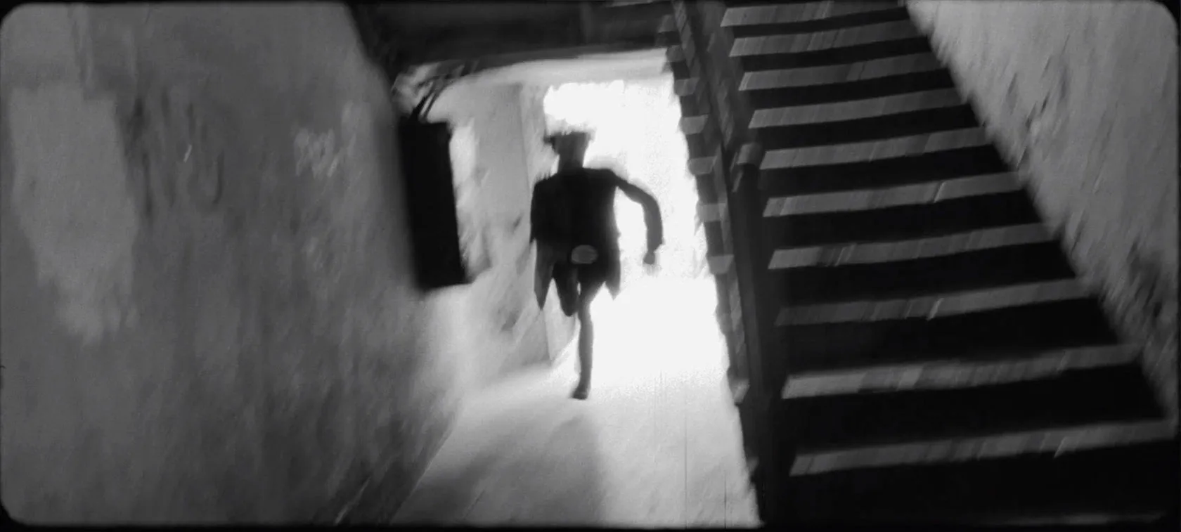A Perfect Job by Andrei Kovalev: a blurred figure runs down a narrow, dimly lit stairwell.