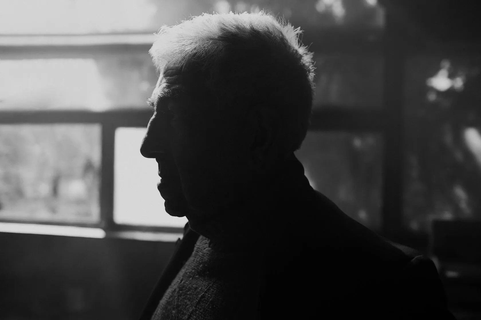Robert in profile against a bright window, in black and white.