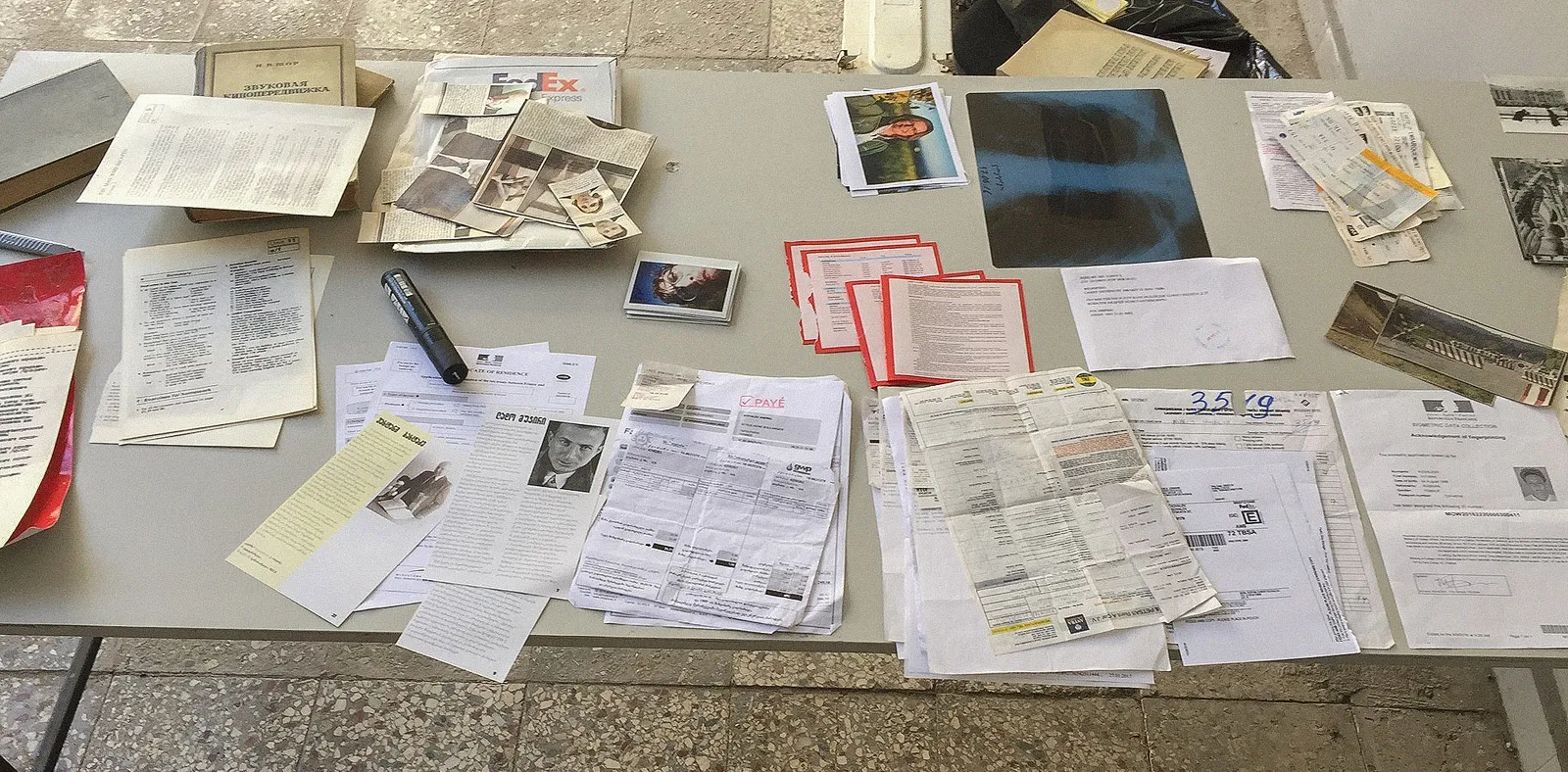 A long table covered in papers, photos, an X-ray and notes.