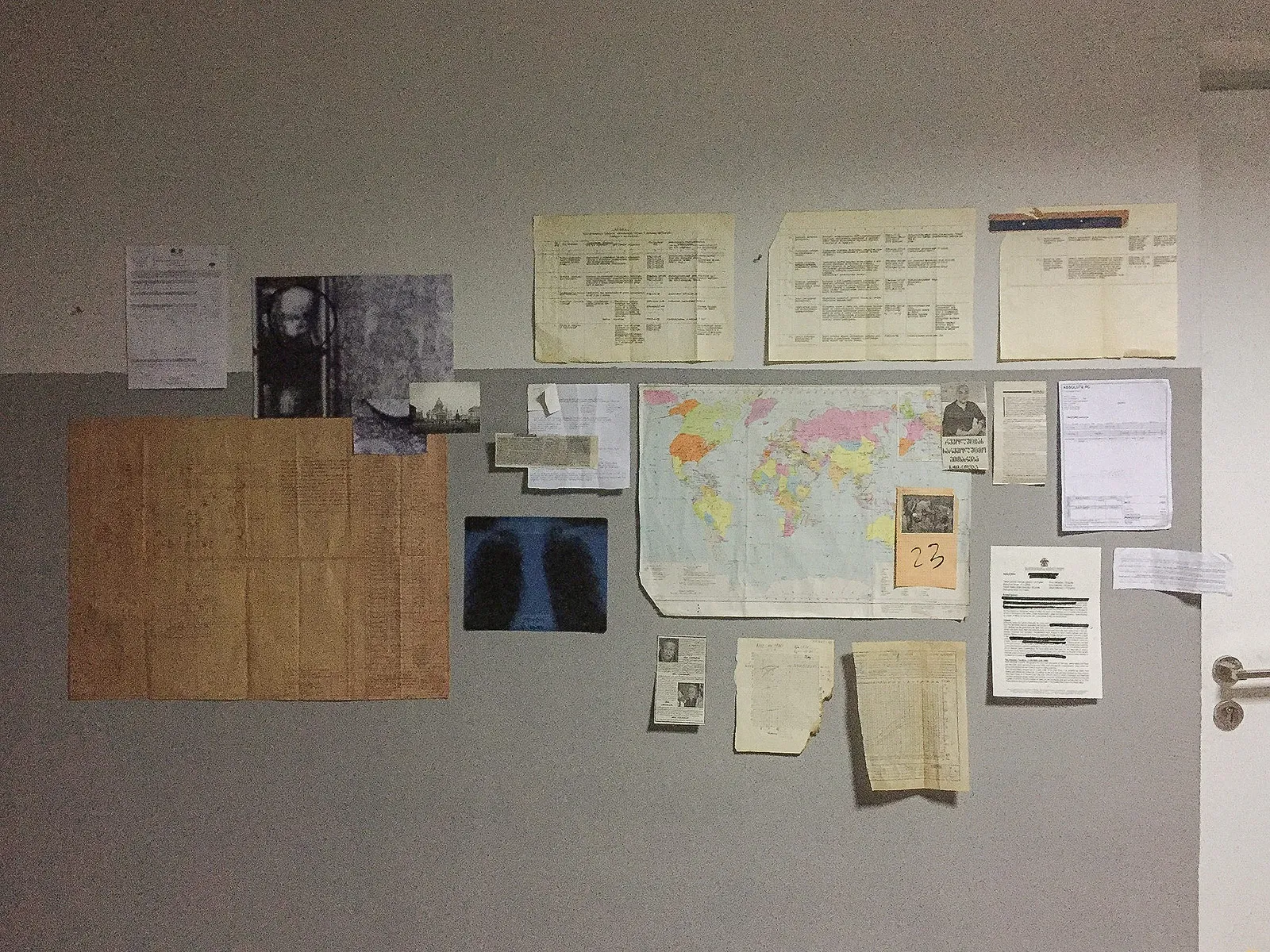 A wall of notes, a world map, an X-ray and an old photo.