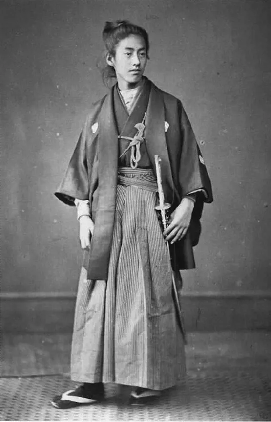 Reference: a 19th-century studio portrait of a young samurai in kimono and hakama, a sword at his side.