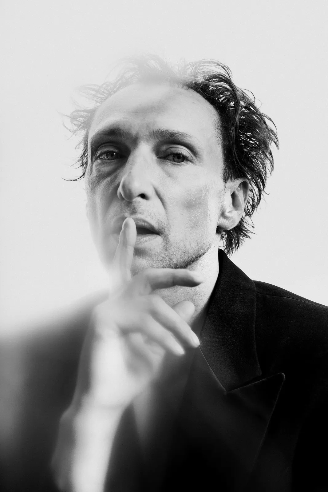 The actor raises a finger to his lips, in black and white.