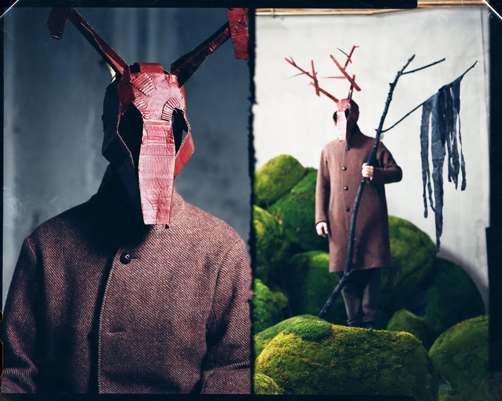 A red antlered mask in close-up, and its wearer in a brown coat on mossy rocks.
