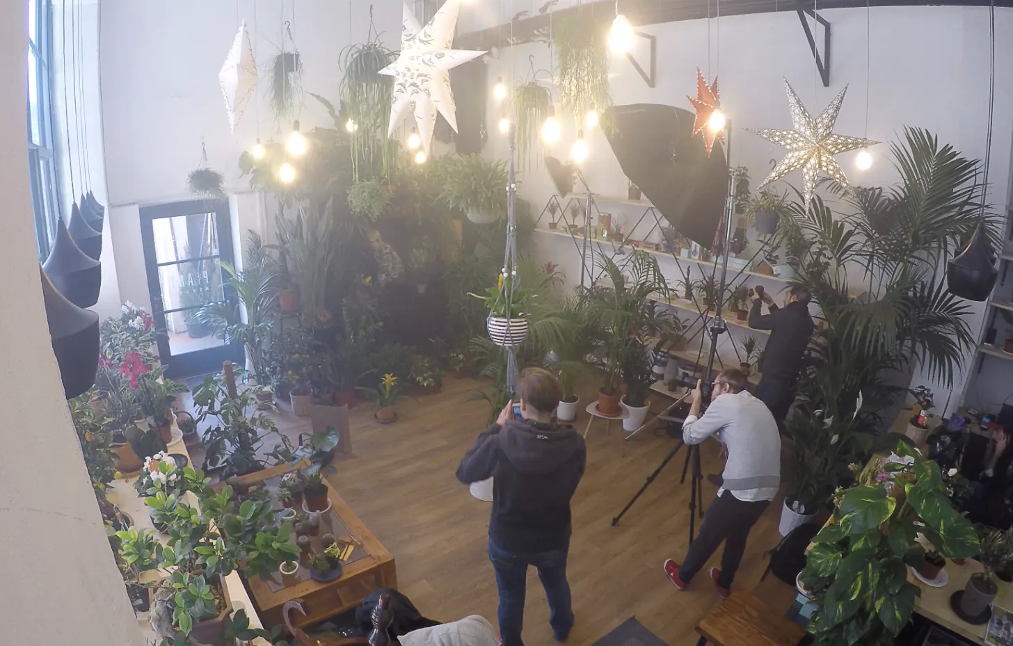 Lights, a camera and crew among the plants of the shop, seen from above.