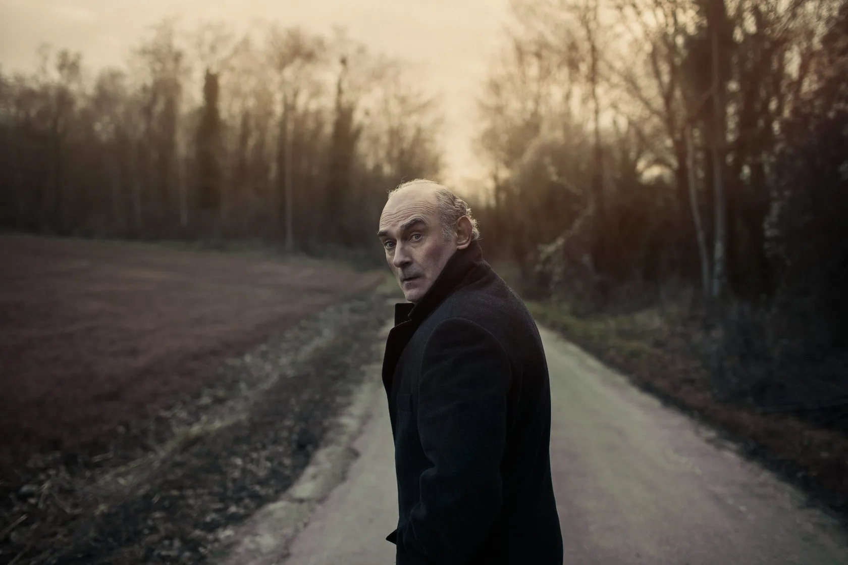 Michel Honaker looks back over his shoulder on a country road at dusk.