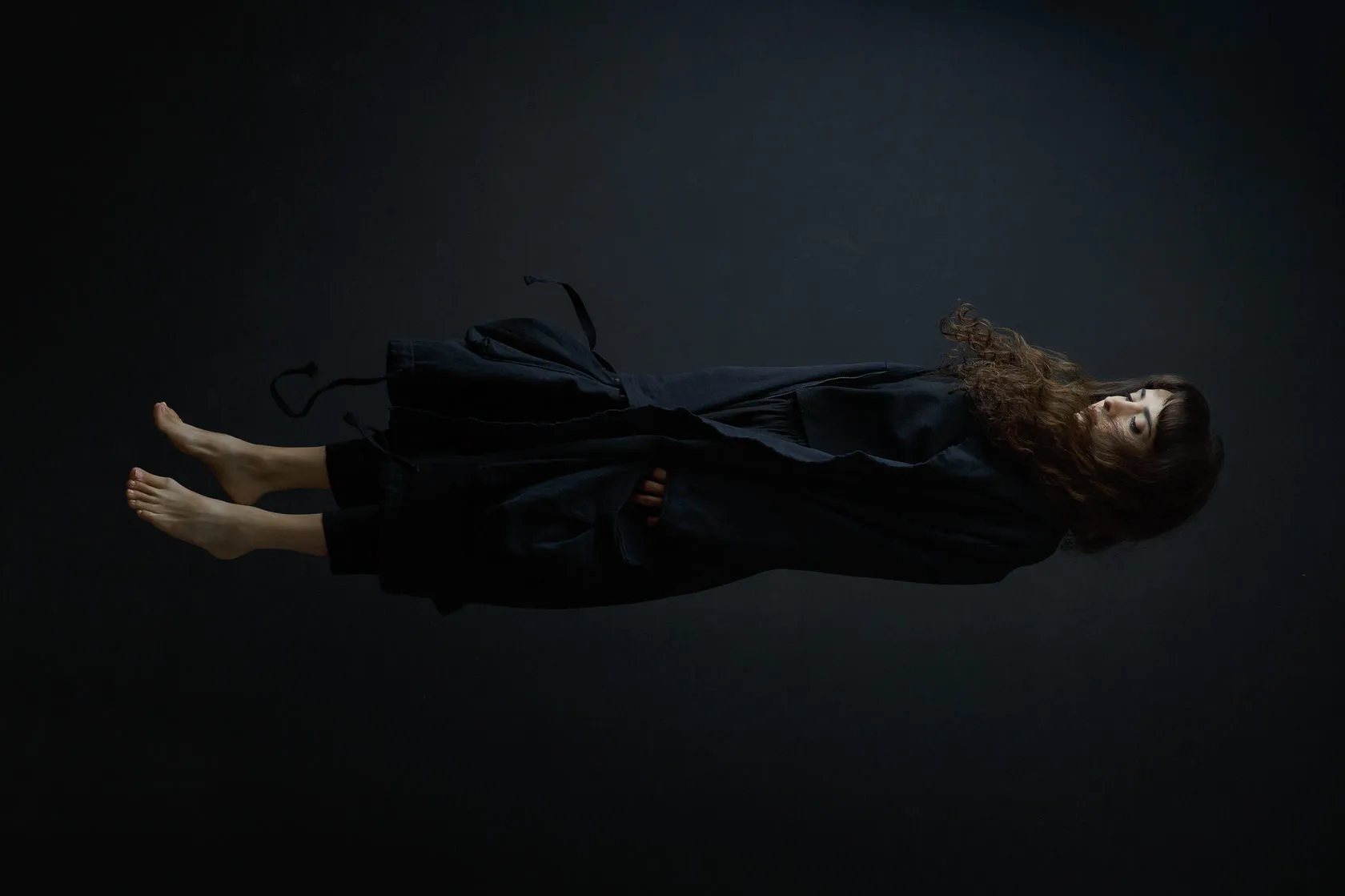 Nana Ekvtimishvili floats barefoot in the dark, eyes closed, in a black coat.