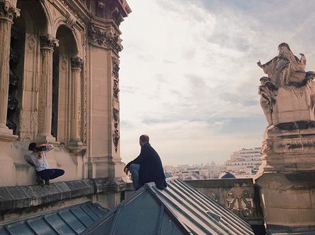 Behind the scenes on the roof: I crouch on a ledge while Laurent sits on the roof ridge.