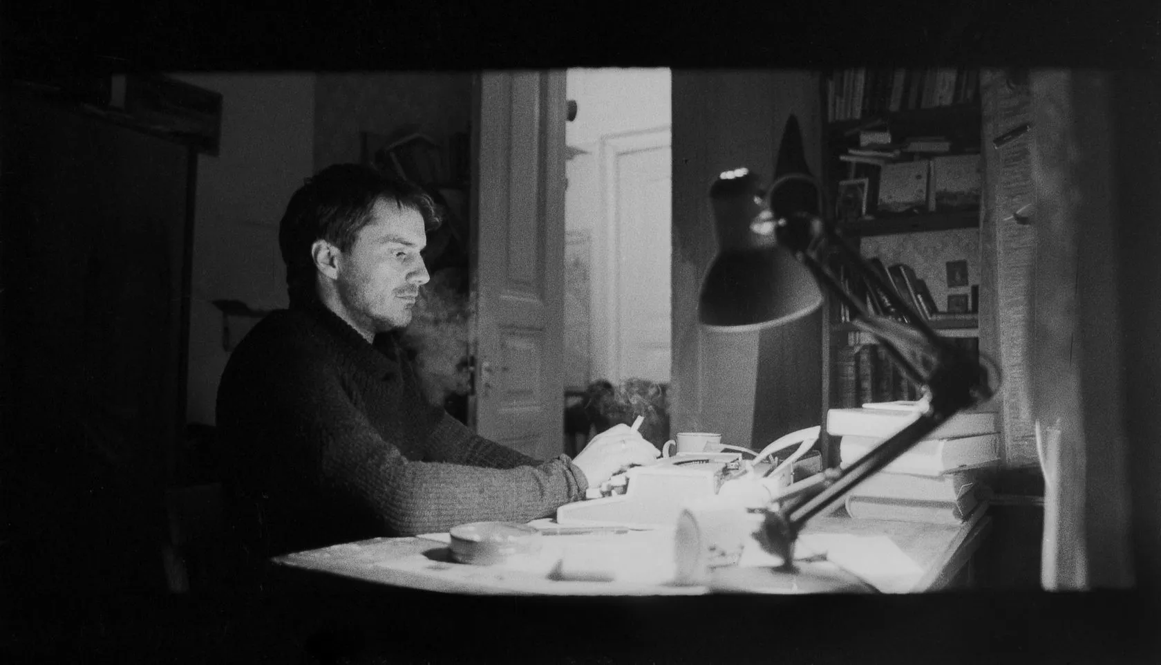 Sven writes at a lamp-lit desk in a black-and-white film frame.