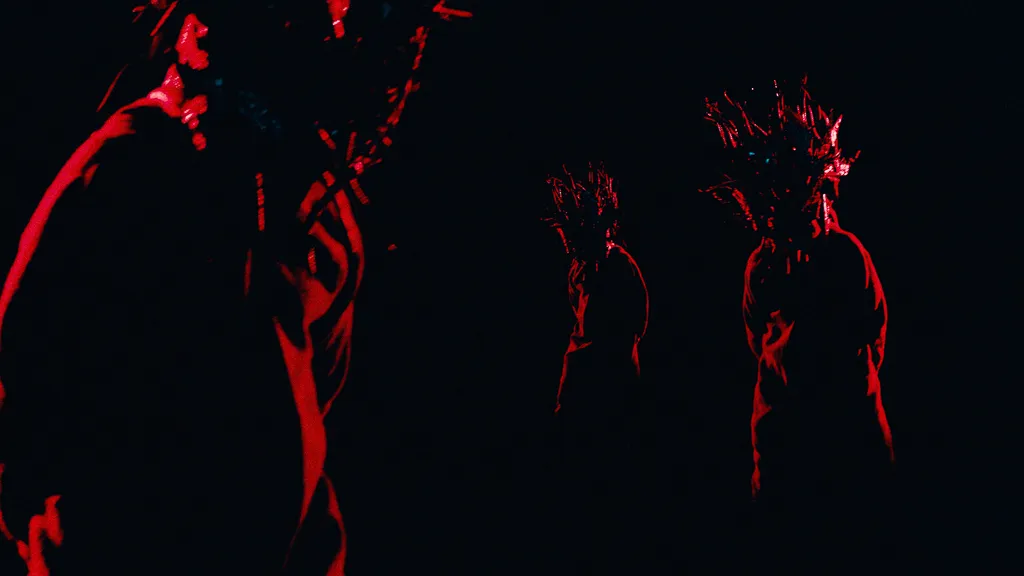 Red silhouettes of the masked figure, one close up and two in the distance.