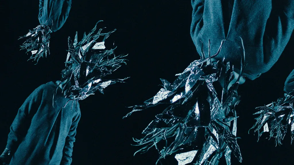 Copies of the masked figure tumble upside down across the frame.