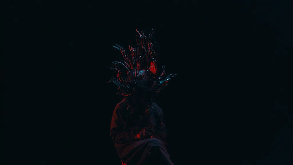 The masked figure in the dark, red light catching the foil.