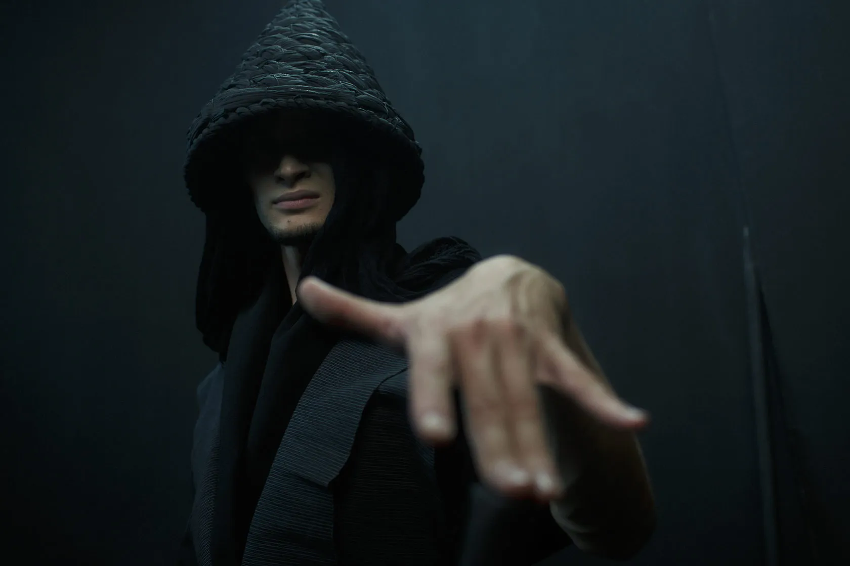 A man in a woven conical hat reaches a hand towards the camera.