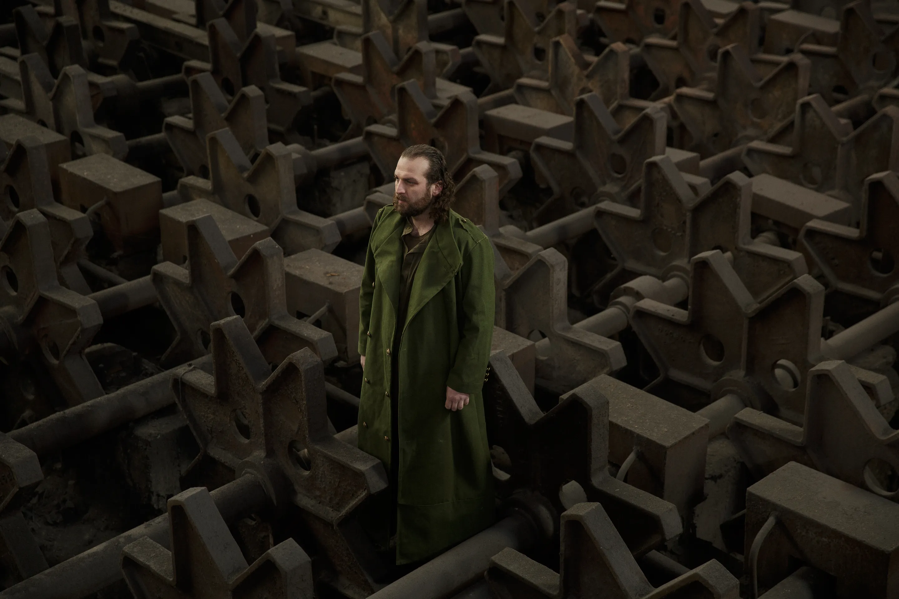 Theatre portfolio by Andrei Kovalev: a man in a long dark coat walks through a maze of small concrete house models.