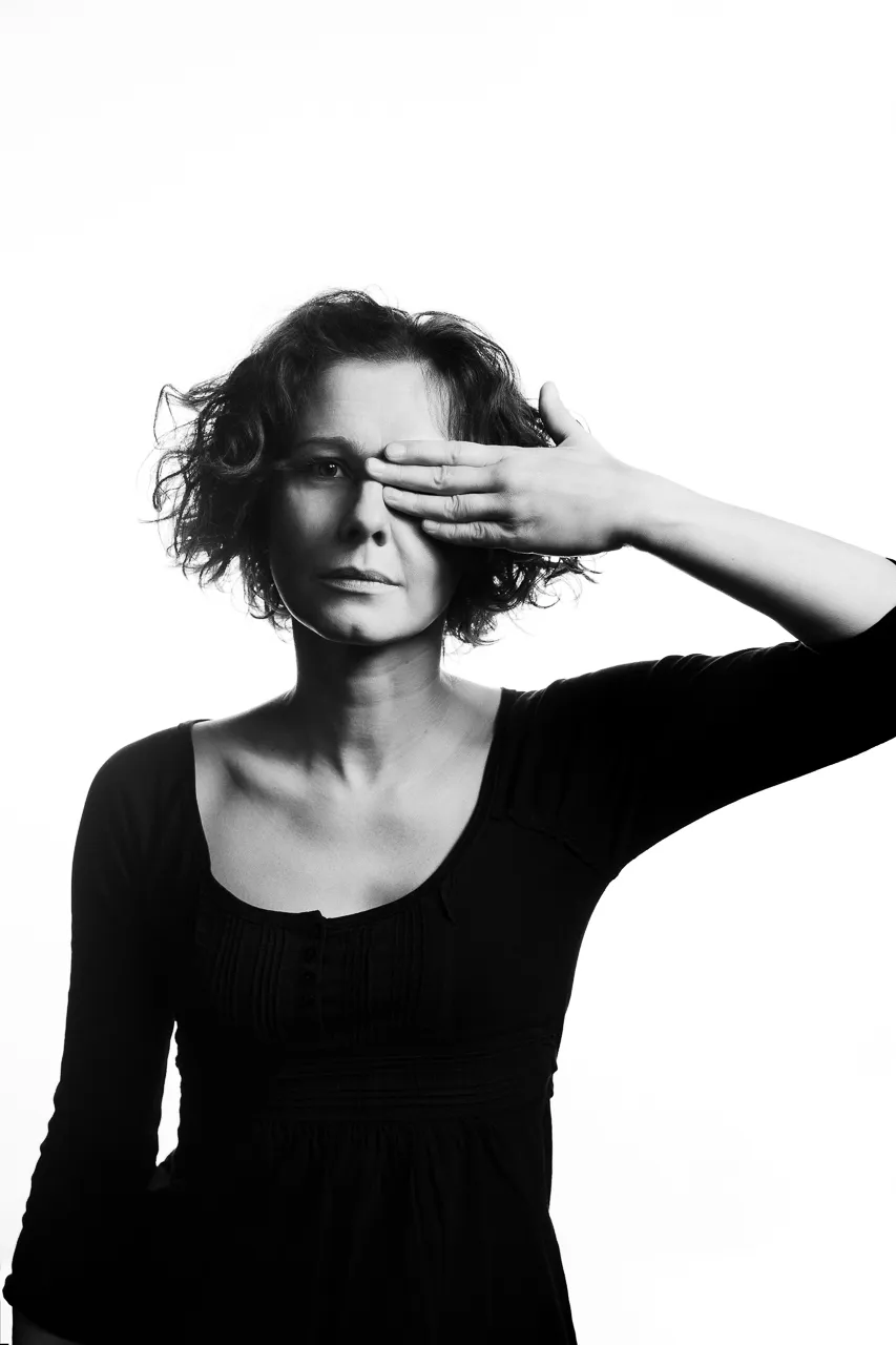 An actress covers one eye with her hand.