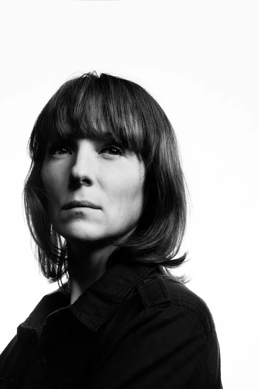 An actress with a fringe looks past the camera.
