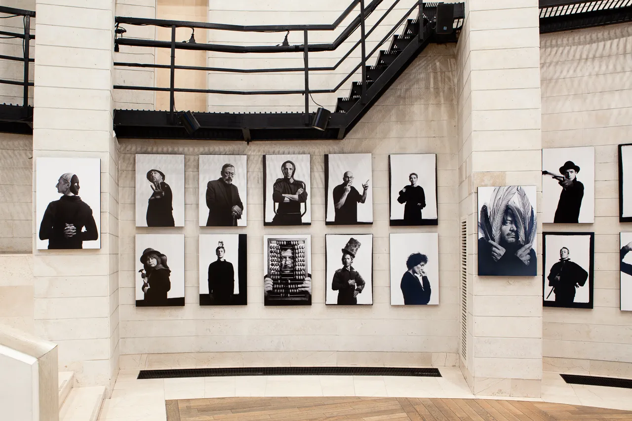 Two rows of portraits hang beneath a black steel staircase.