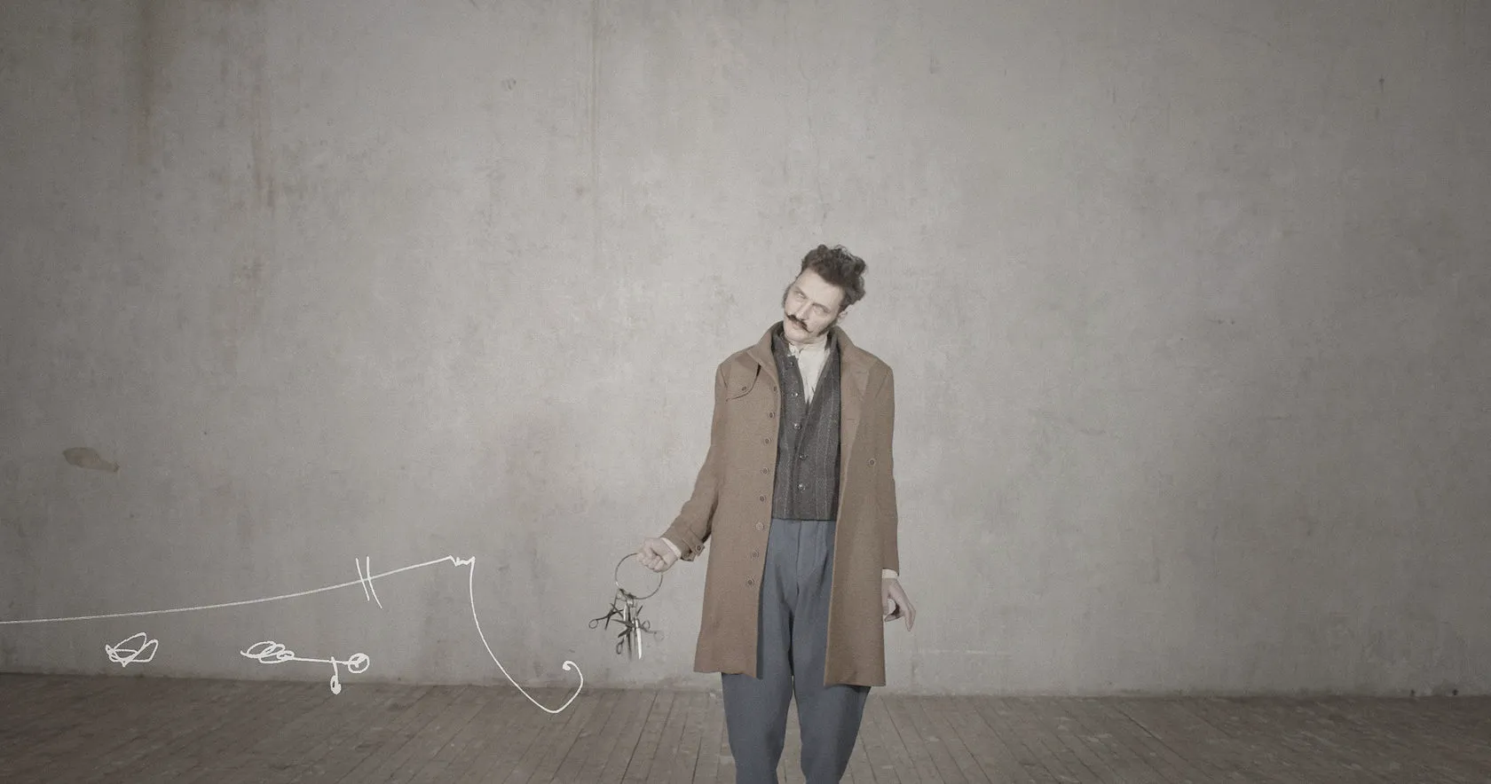 A man in a long brown coat holds a ring of keys as white scribbles trail across the floor.
