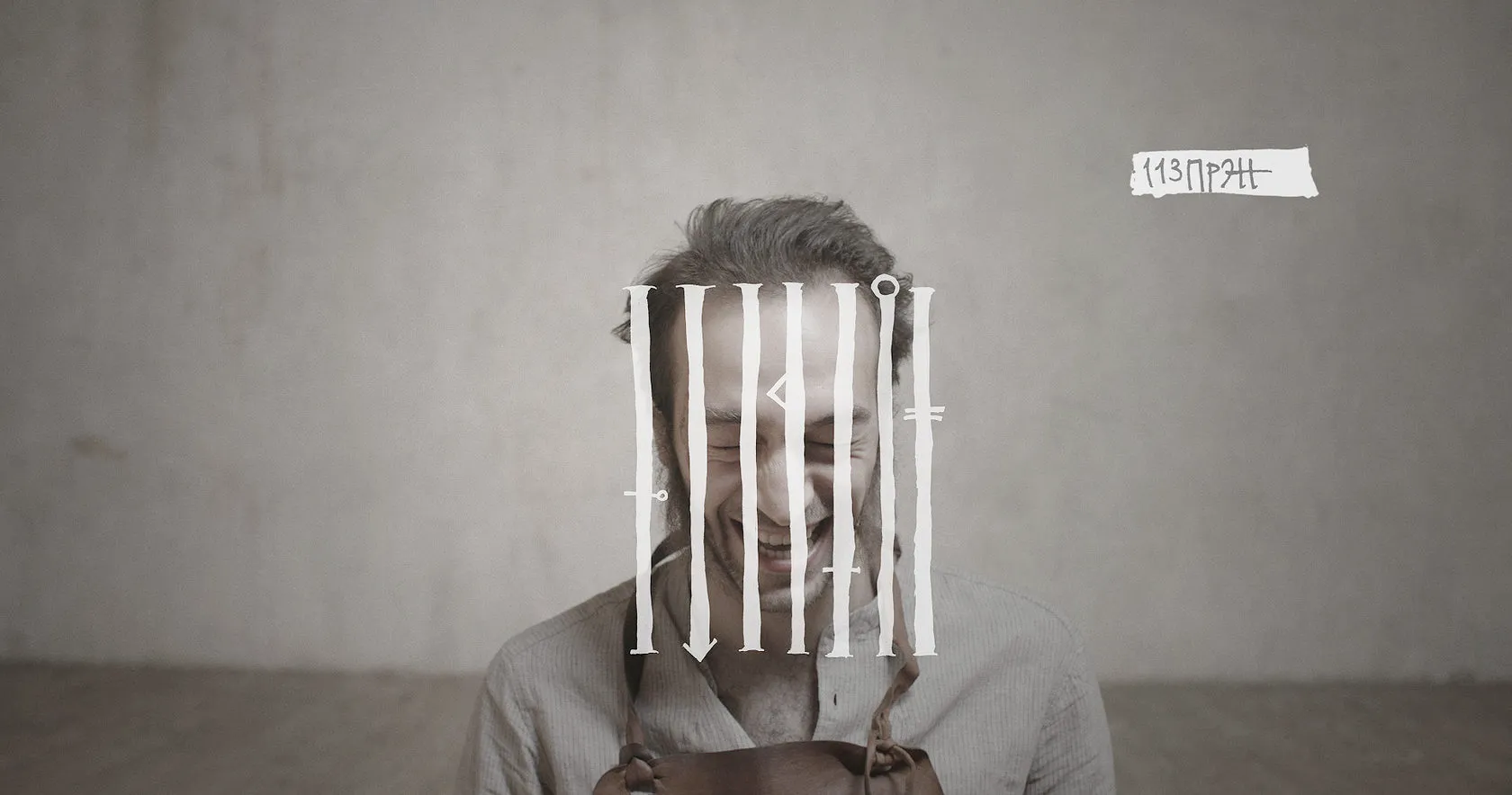 A grinning man behind white prison bars drawn over his face.