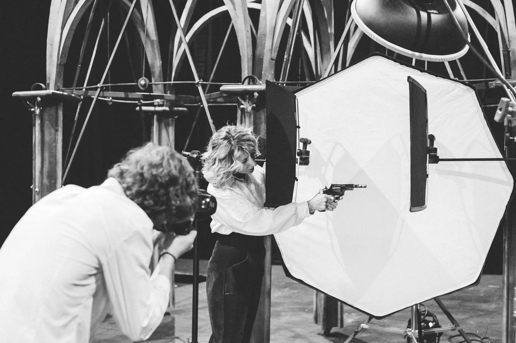 Behind the scenes: the photographer shoots an actress aiming a revolver, under the set’s Gothic arches.