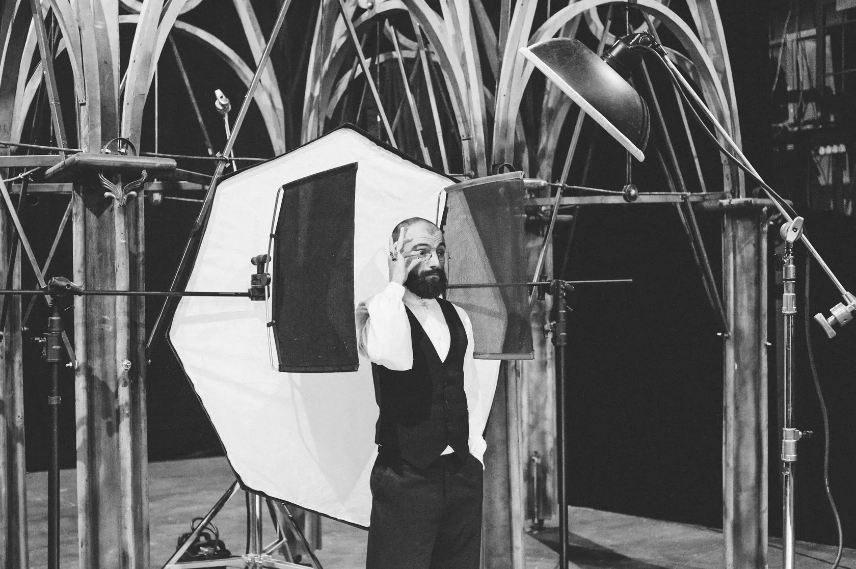 Behind the scenes: a bearded actor in a waistcoat poses under the Gothic arches.