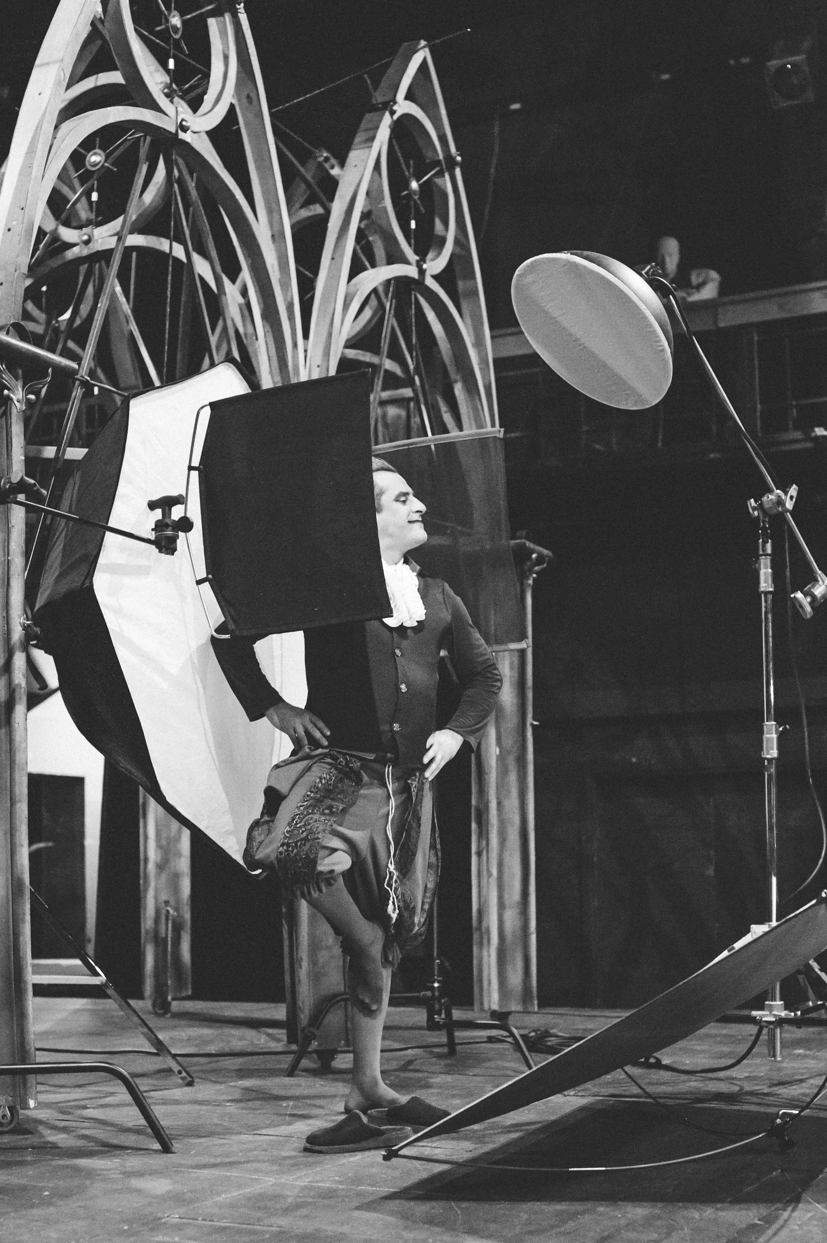 Behind the scenes: an actor in a ruff and puffed breeches poses with one foot raised.
