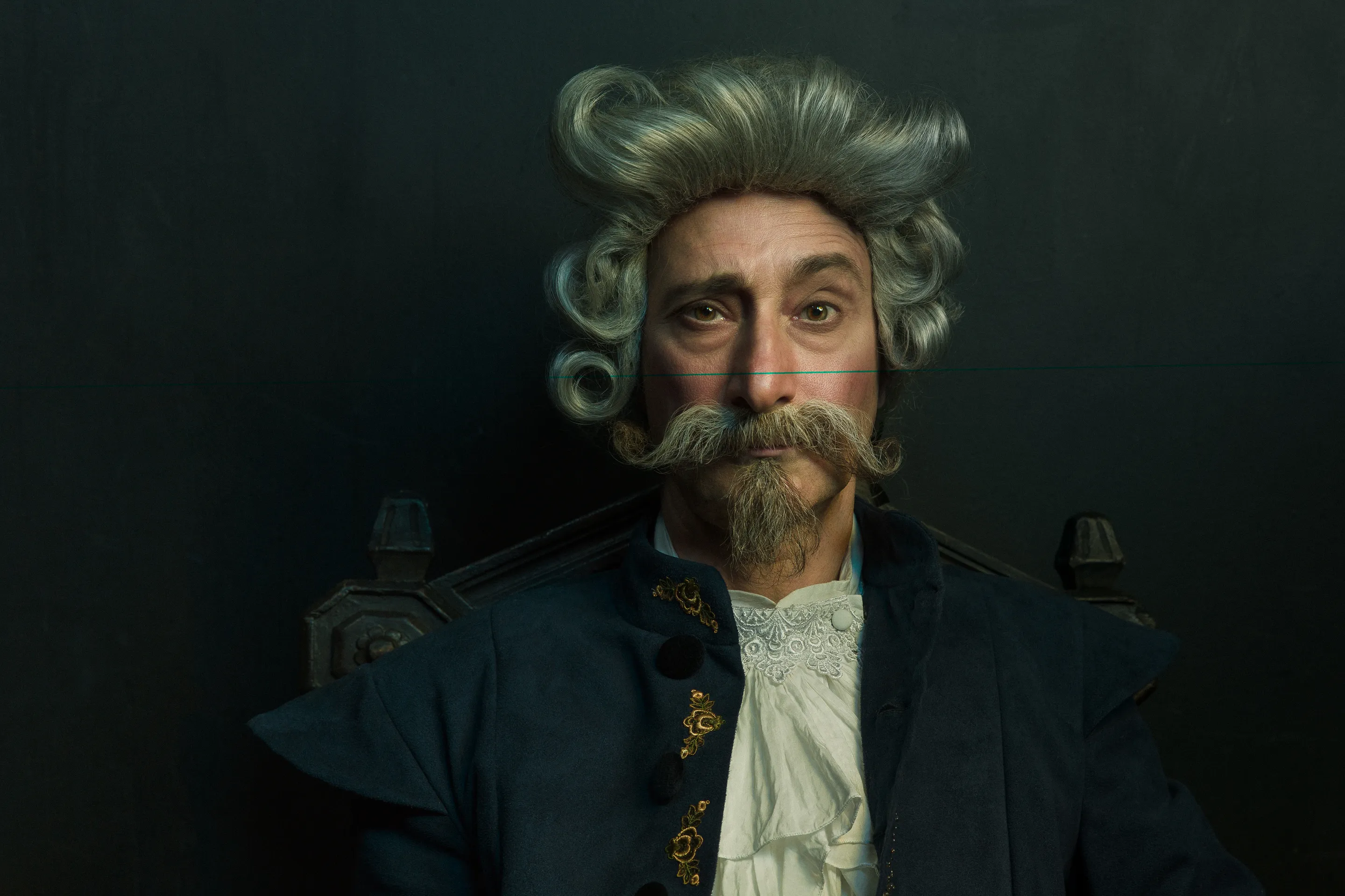 Baron Munchausen key visual by Andrei Kovalev: an actor poses in an elaborate powdered wig and moustache as the Baron.