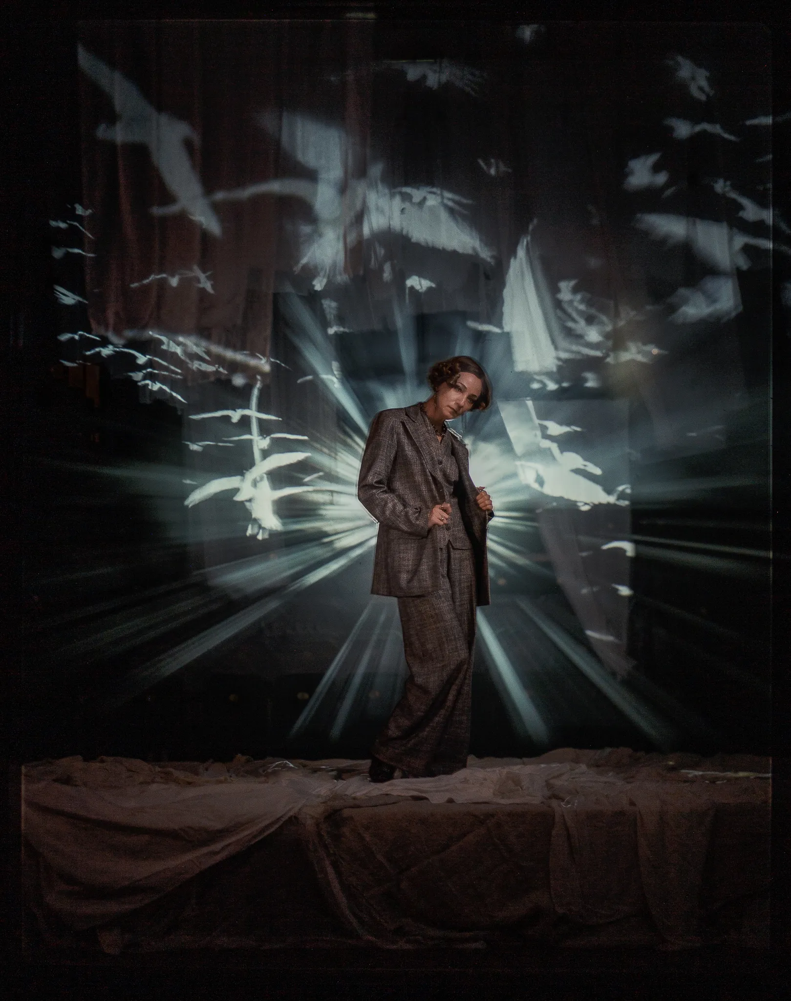 Galina Tyunina as Arkadina in a tweed suit, framed by rays of light and projected gulls.