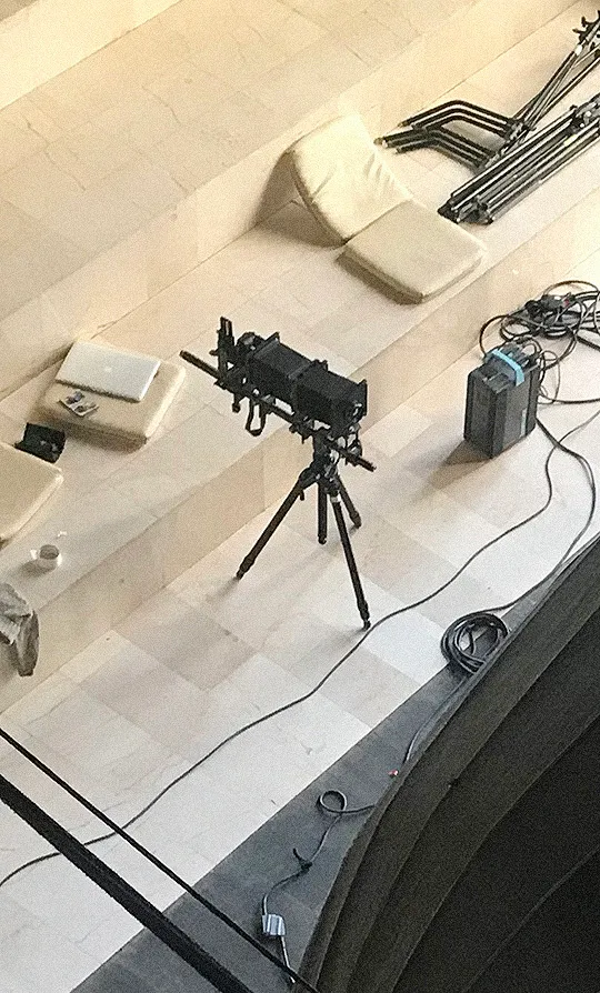 A 4×5 field camera on a tripod, seen from the balcony above the set.