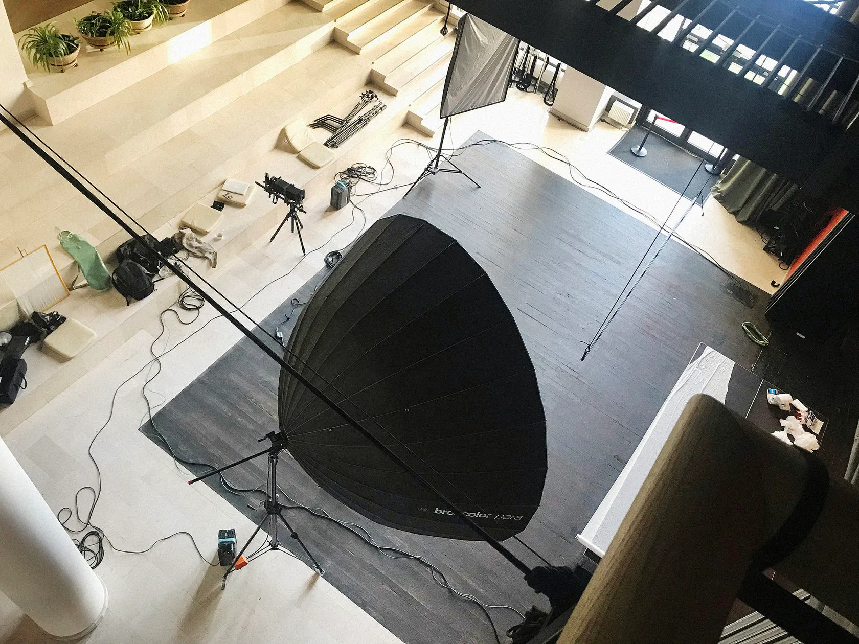 A giant Broncolor Para reflector and light stands on the set floor, seen from the balcony.