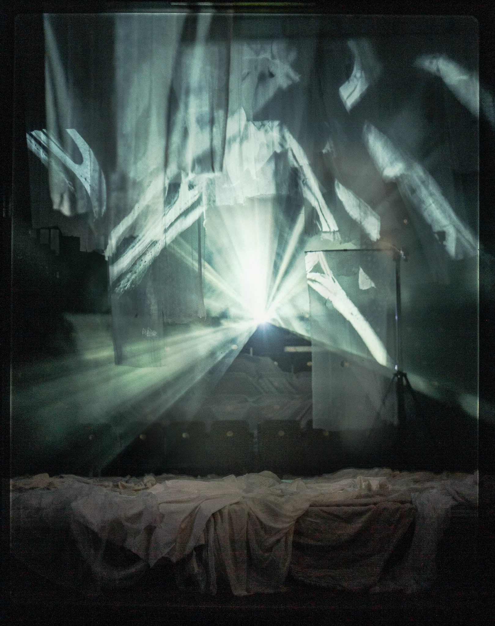 The empty stage: light rays and projected gulls on strips of gauze above a draped platform.