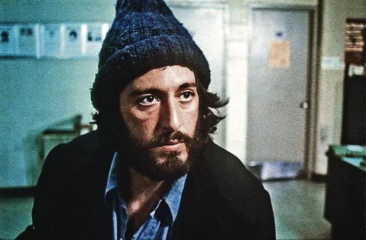Reference: a bearded man in a dark knit cap in a 1970s film still.