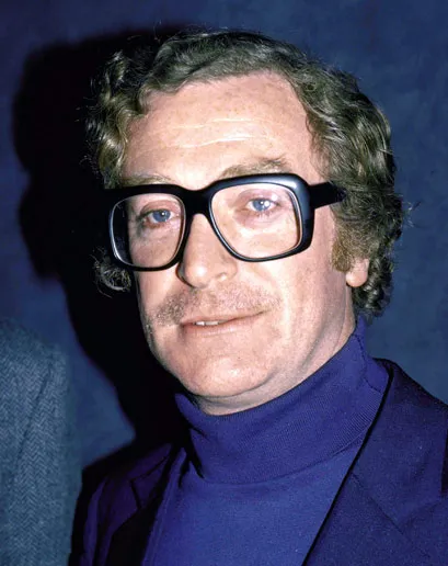 Reference: a man in thick black glasses and a blue polo neck.