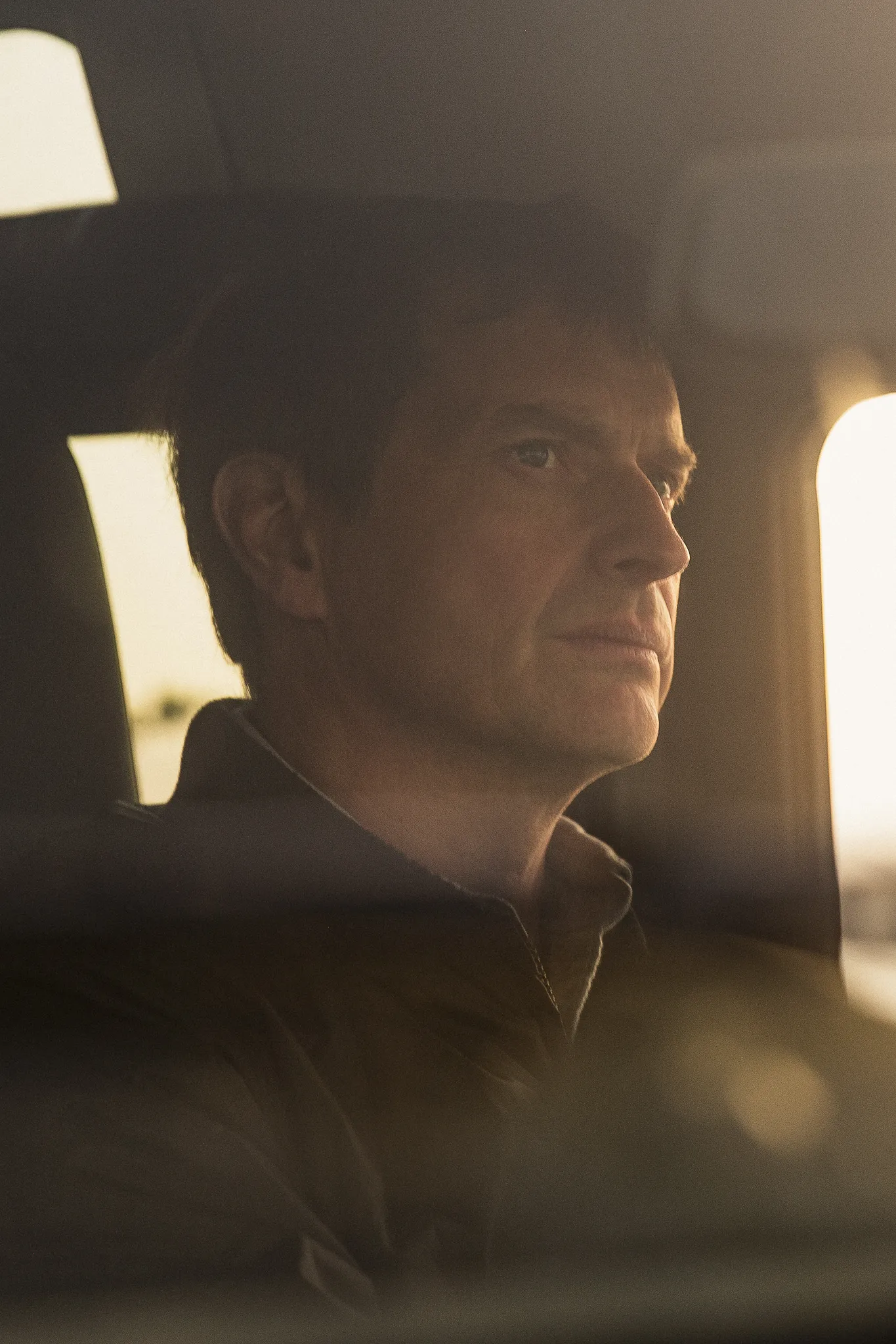 Jean-Louis Chave at the wheel of a car in warm evening light.