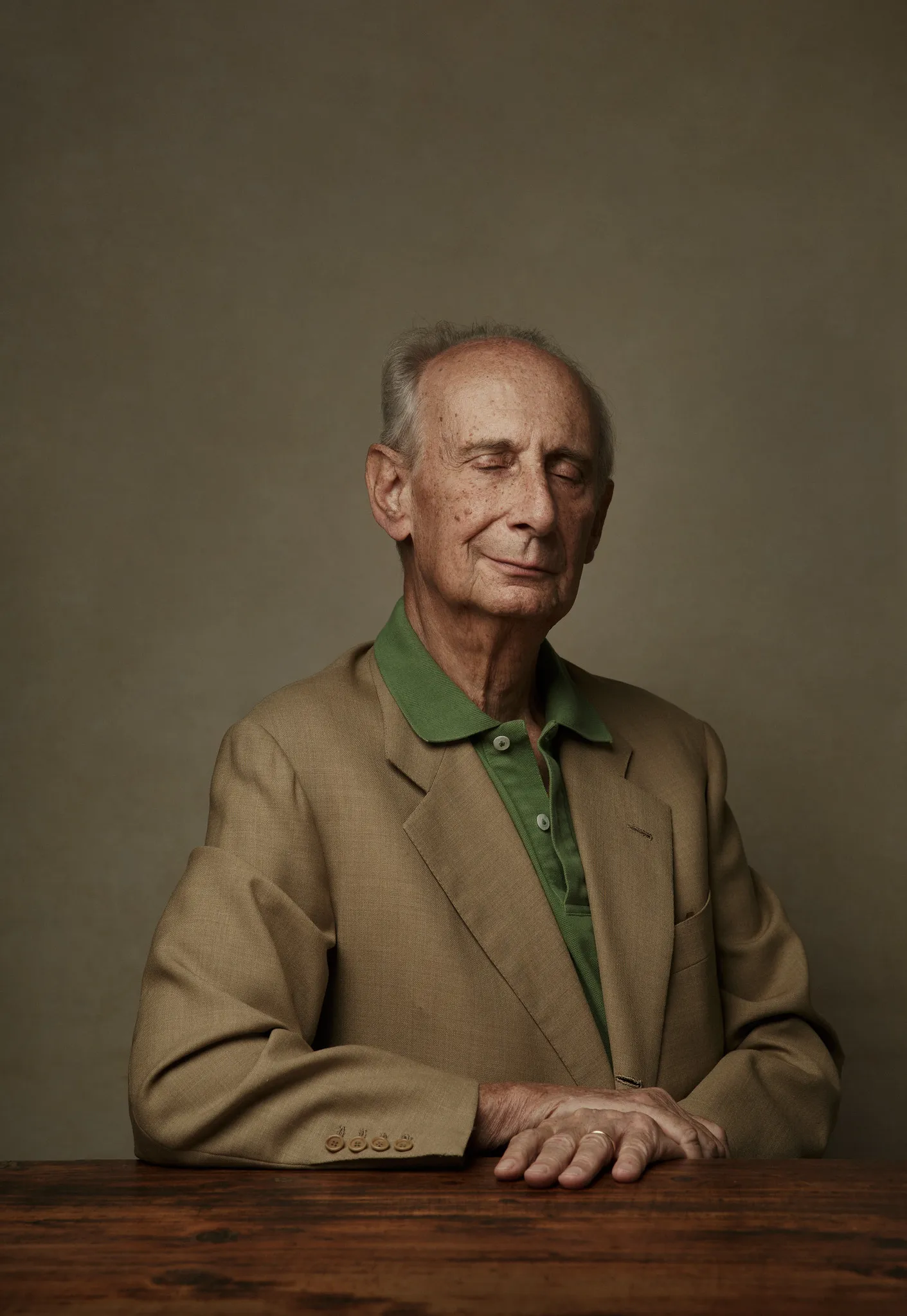 Leonardo Frescobaldi in a tan jacket and green polo sits at a wooden table.