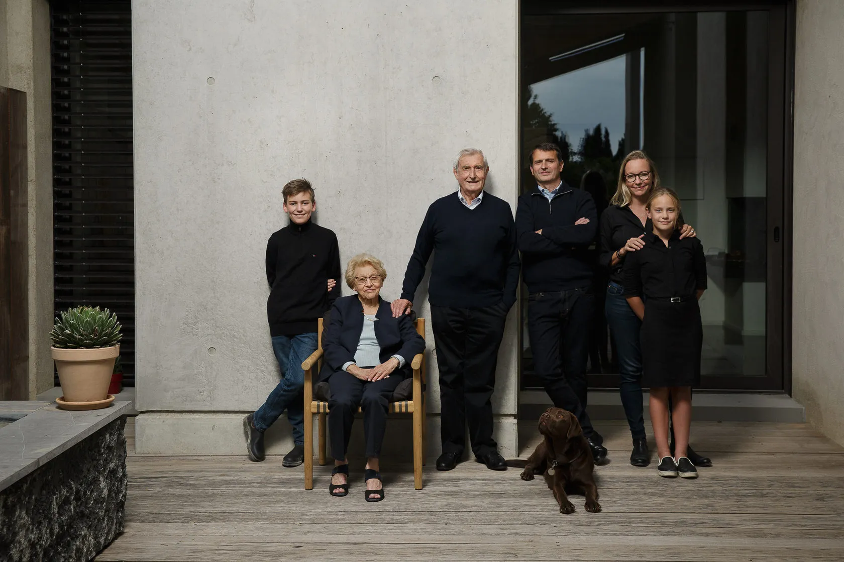 The Chave family together by a concrete wall at home, their dog at their feet.