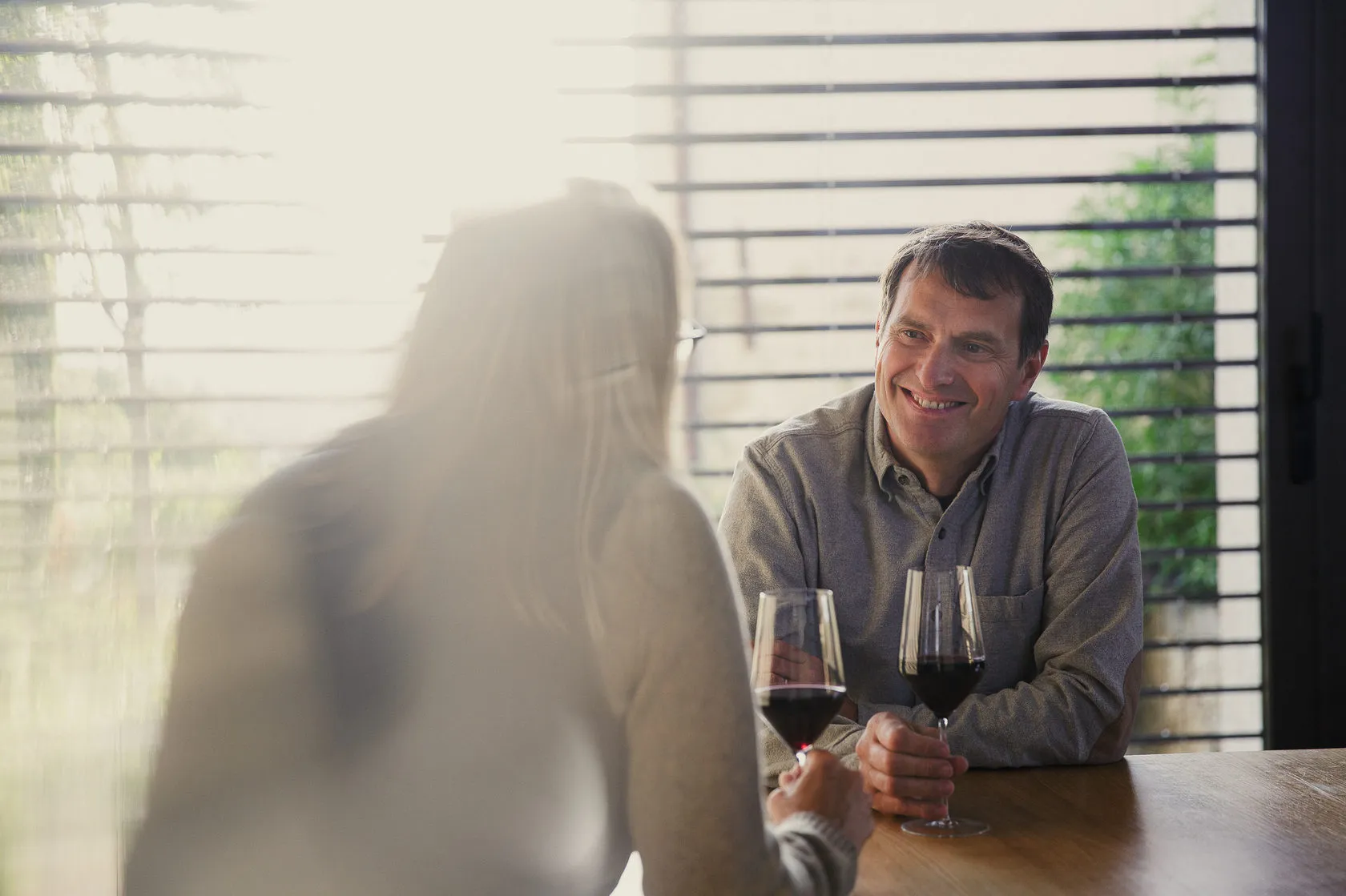 Jean-Louis Chave smiles across a table at a woman, both holding red wine.