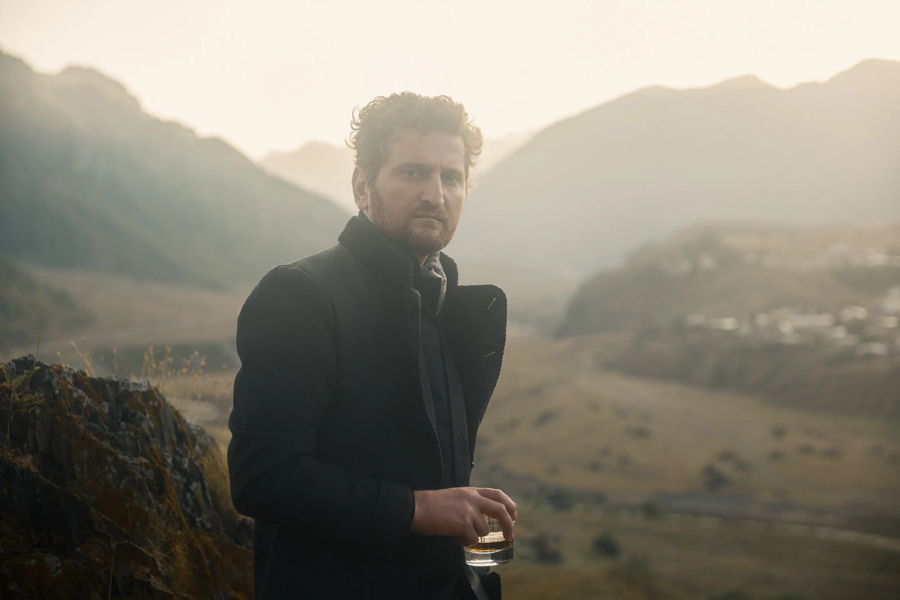 Jimsher campaign by Andrei Kovalev: a man stands in misty mountains, drink in hand, gazing into the distance.