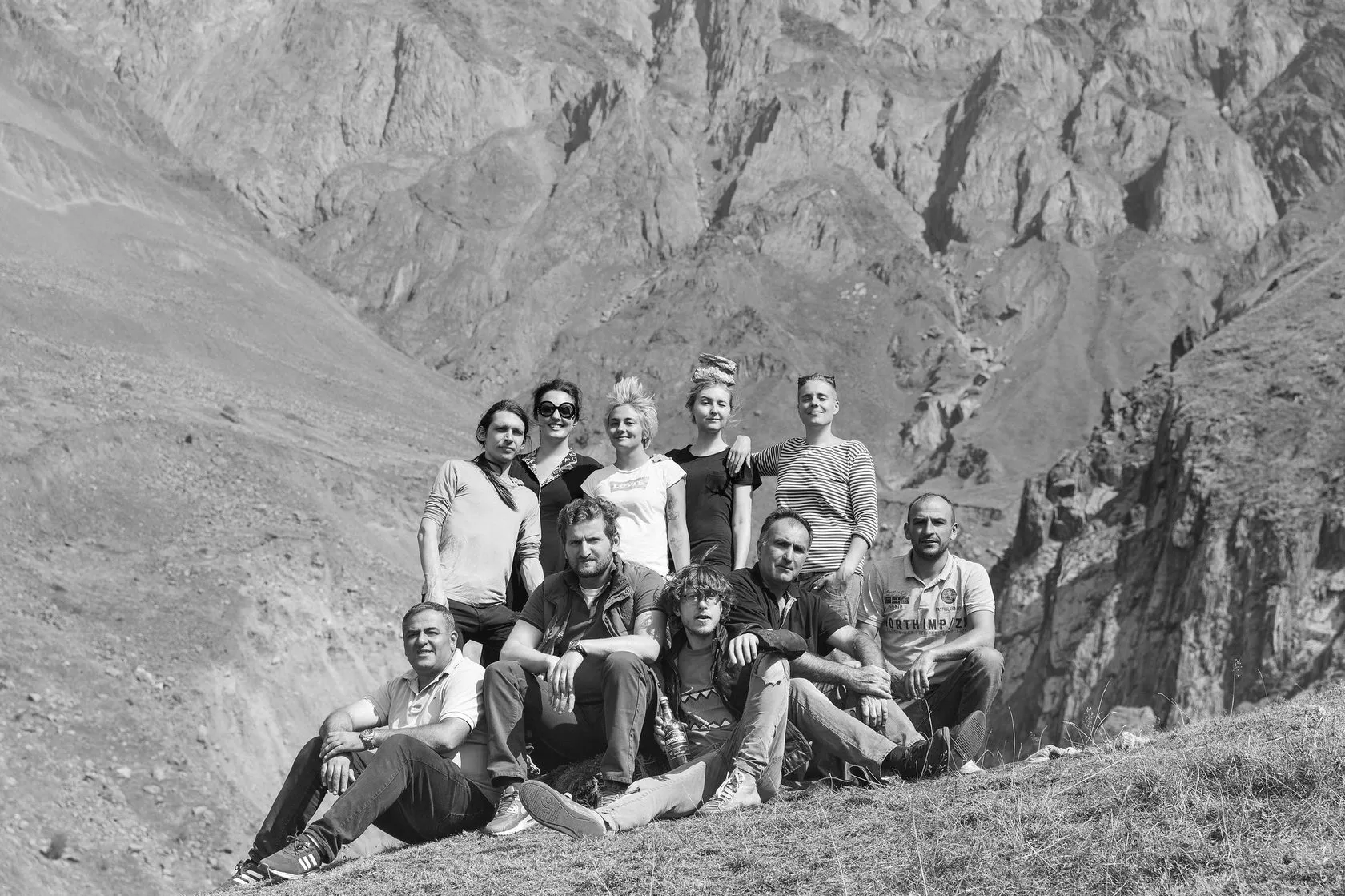 The crew poses together on a mountain slope, in black and white.