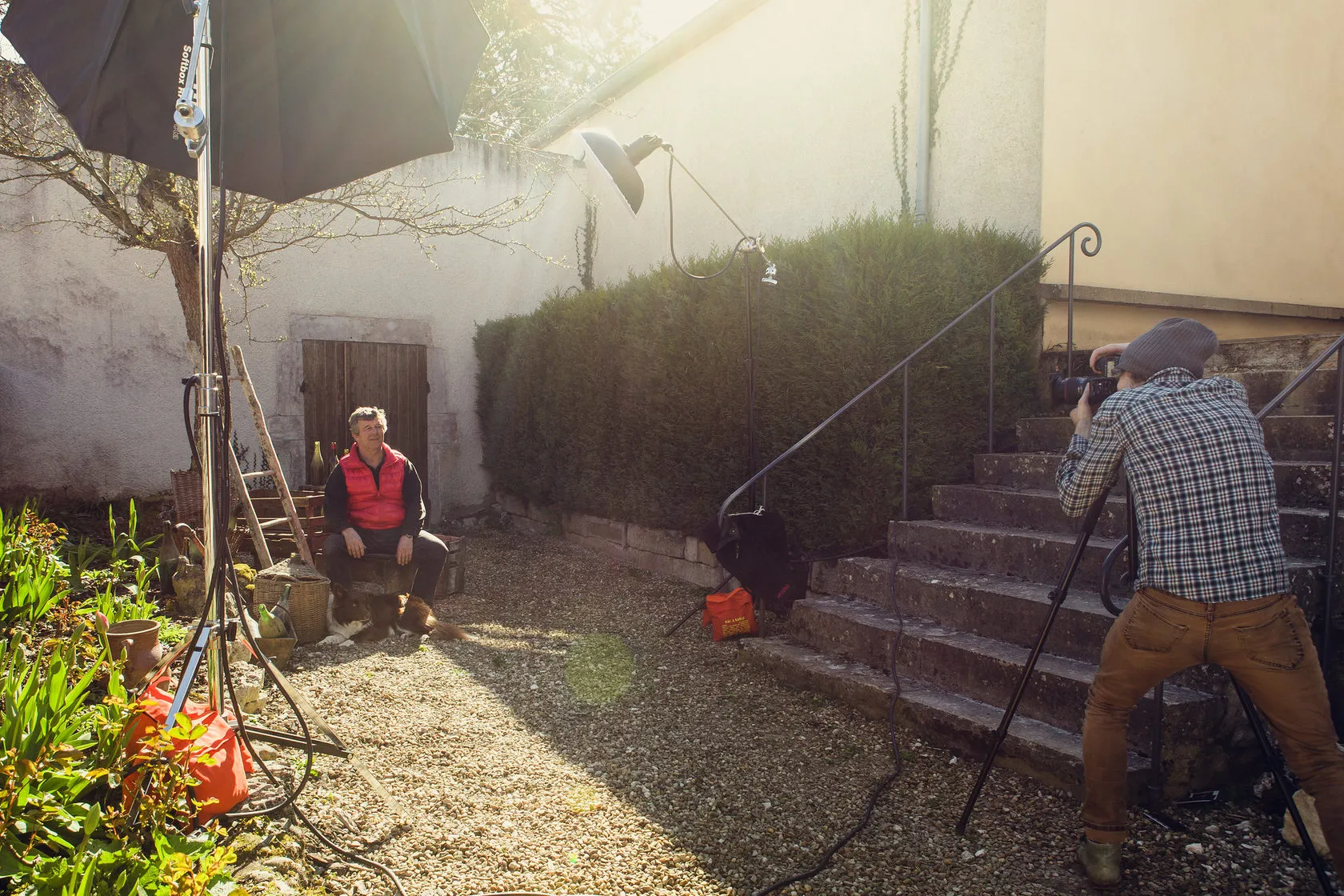 Behind the scenes: a winemaker sits in a sunny courtyard while a photographer shoots from the steps.
