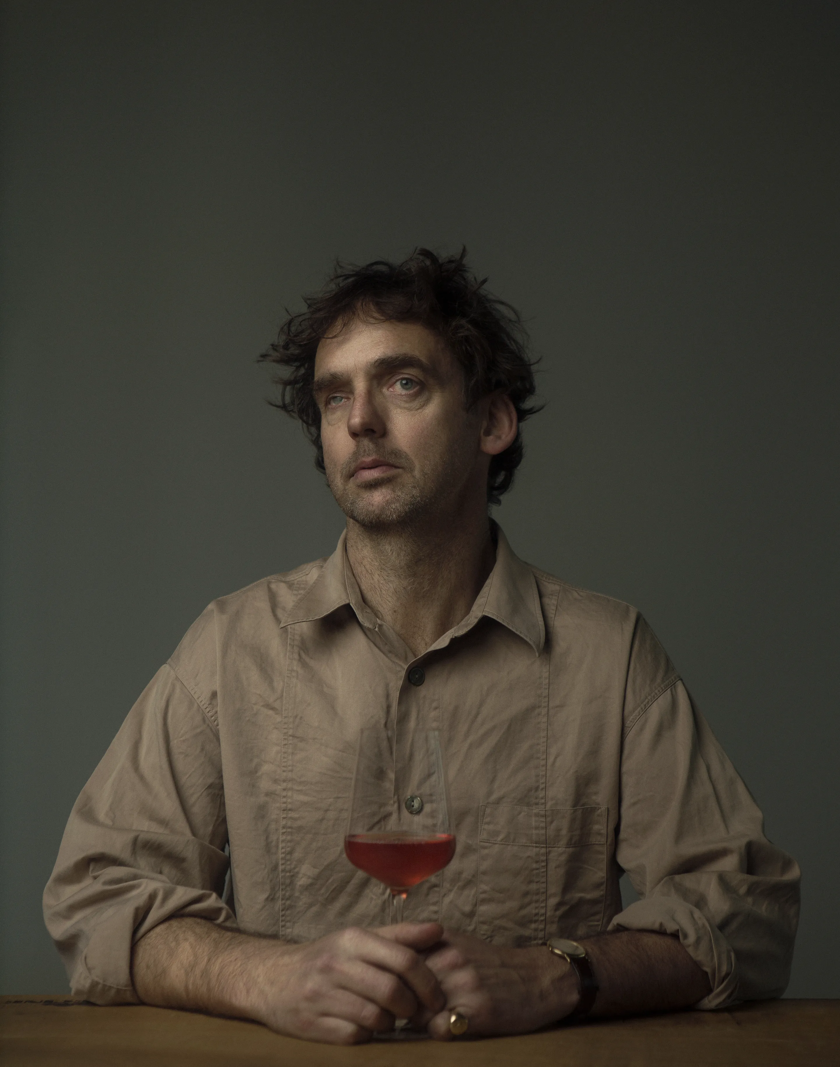 The Makers portrait series by Andrei Kovalev: Sean O’Callaghan sits at a table with a glass of wine, looking up.