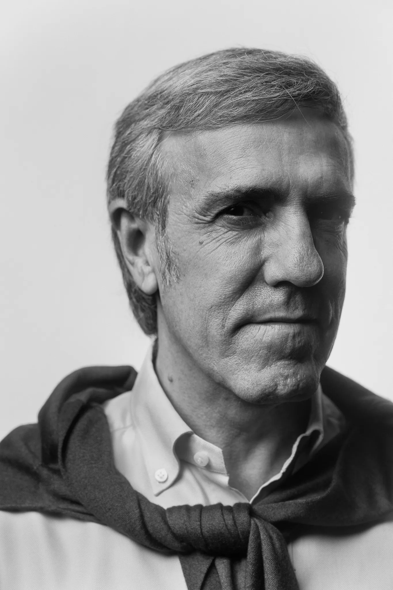 A grey-haired winemaker with a jumper knotted over his shoulders, in black and white.