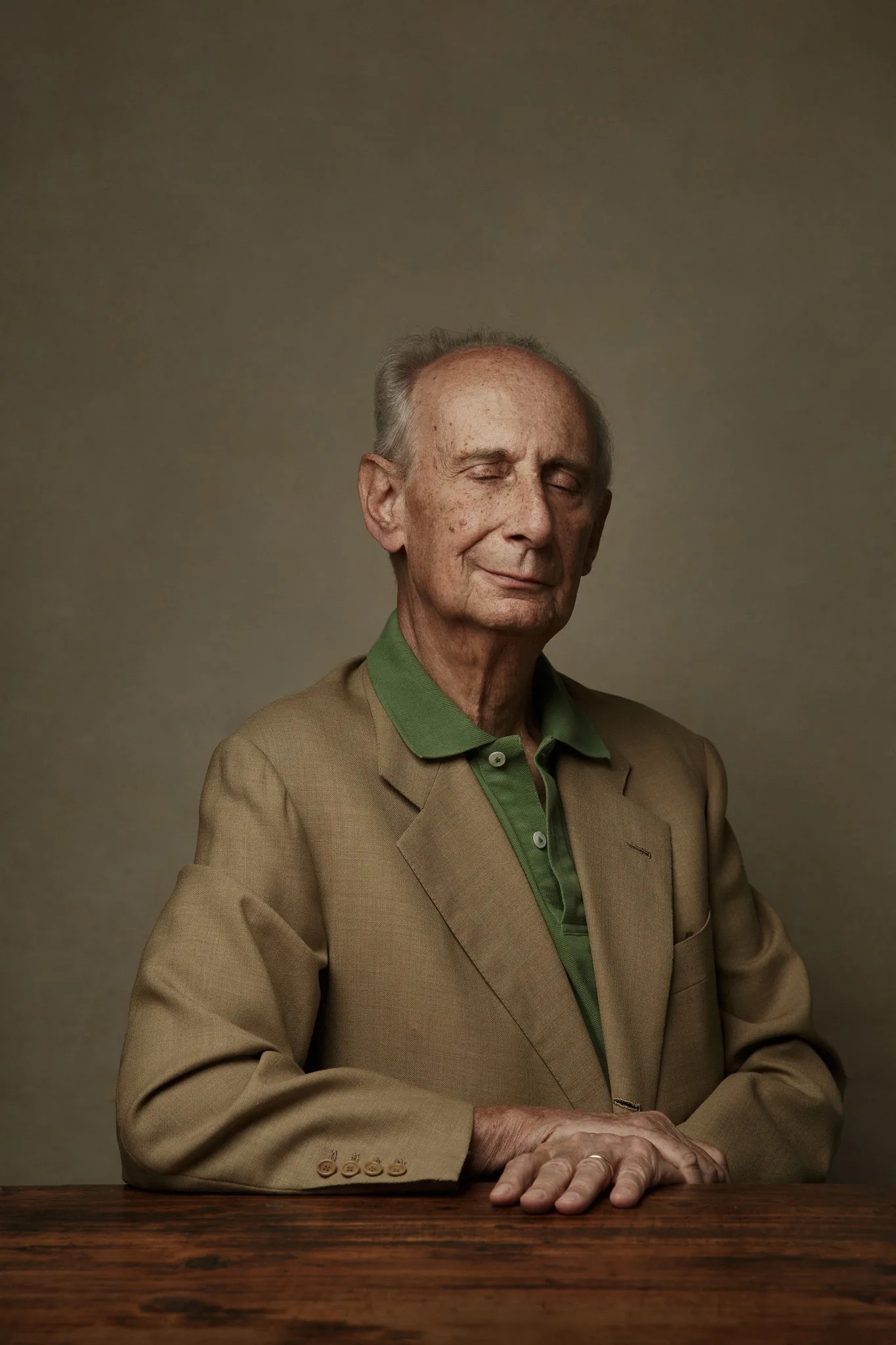Leonardo Frescobaldi in a tan jacket and green polo sits at a wooden table.