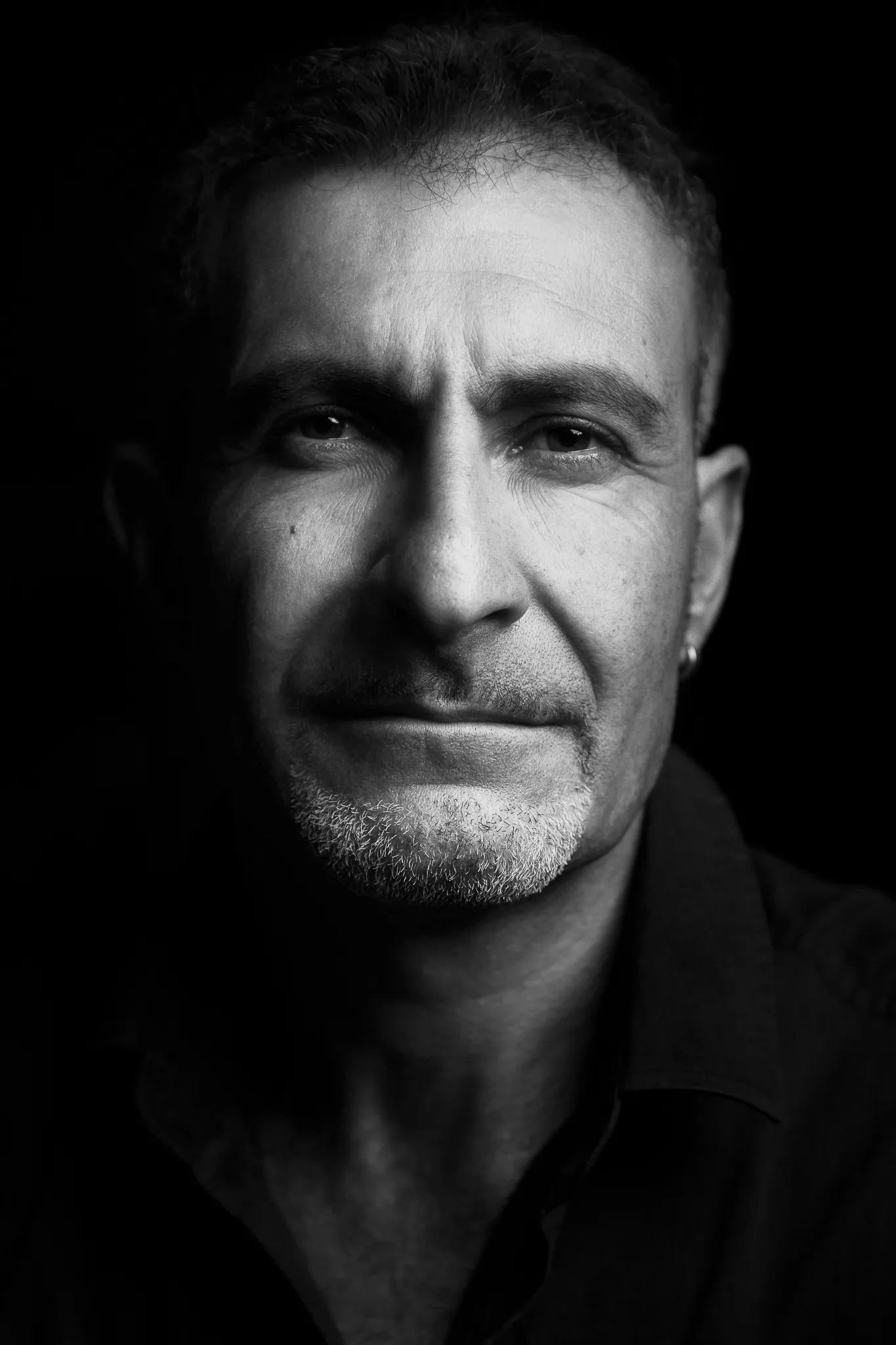 From a campaign for Riecine: a man with grey stubble, half in shadow, in black and white.