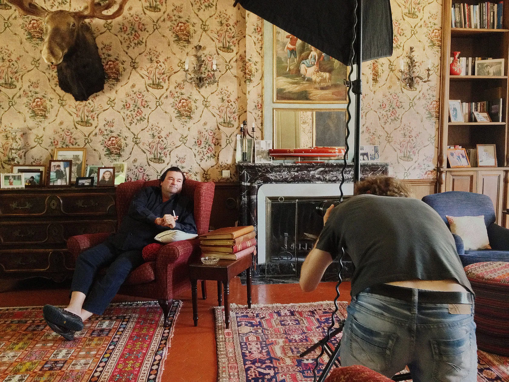 Behind the scenes: a photographer shoots Sacha Alexis Lichine in a red armchair beneath a moose head.