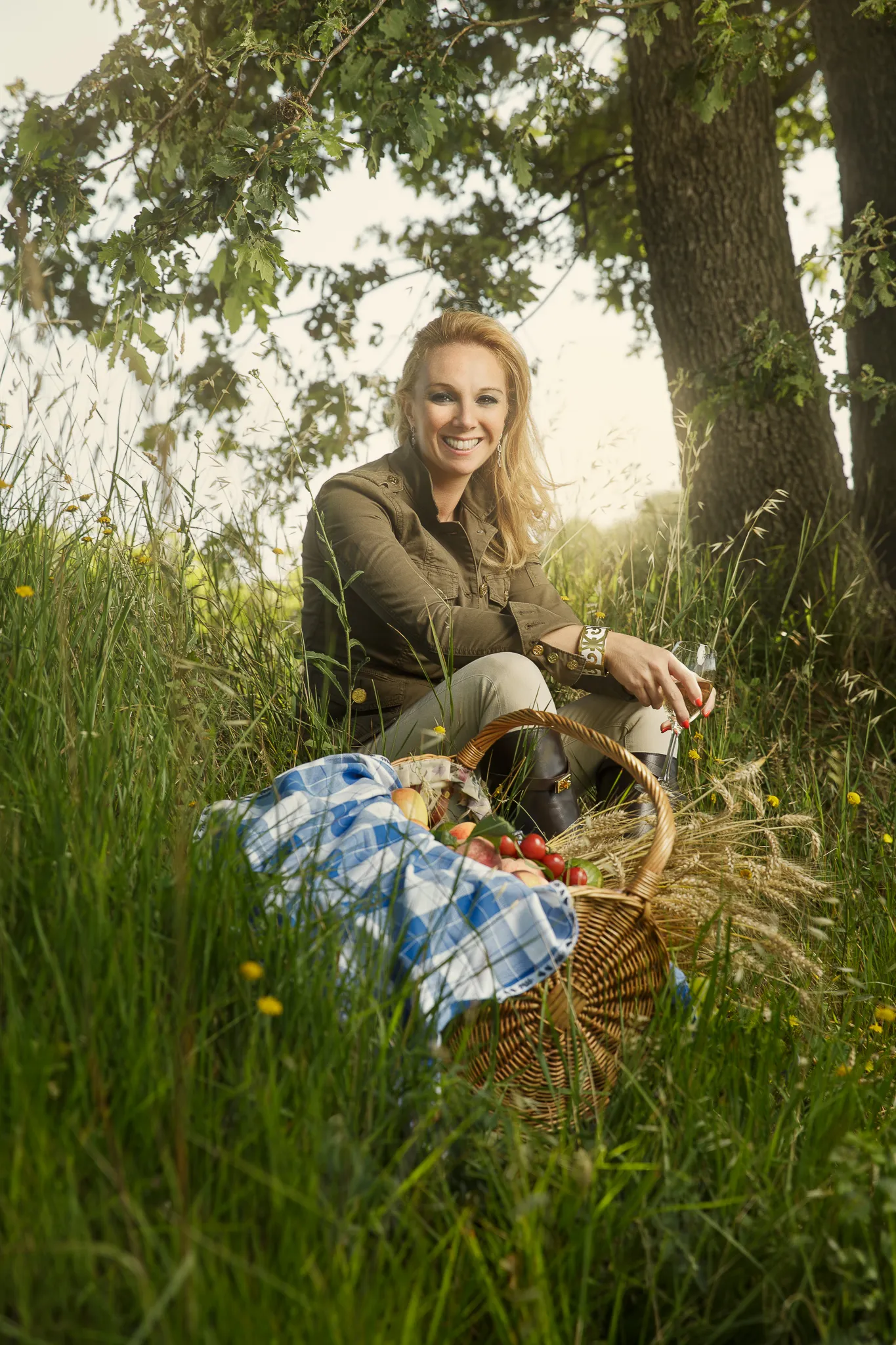 Chiara Soldati sits in long grass under a tree, a picnic basket beside her.