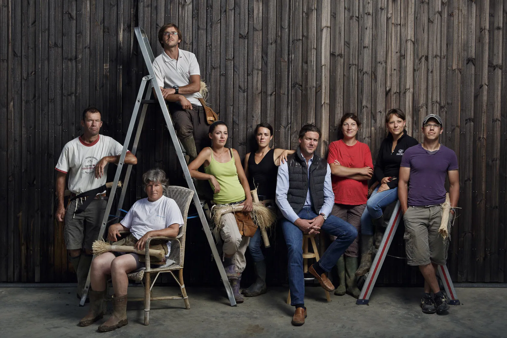 The LaFleur team gathers around a stepladder against a dark wooden wall.