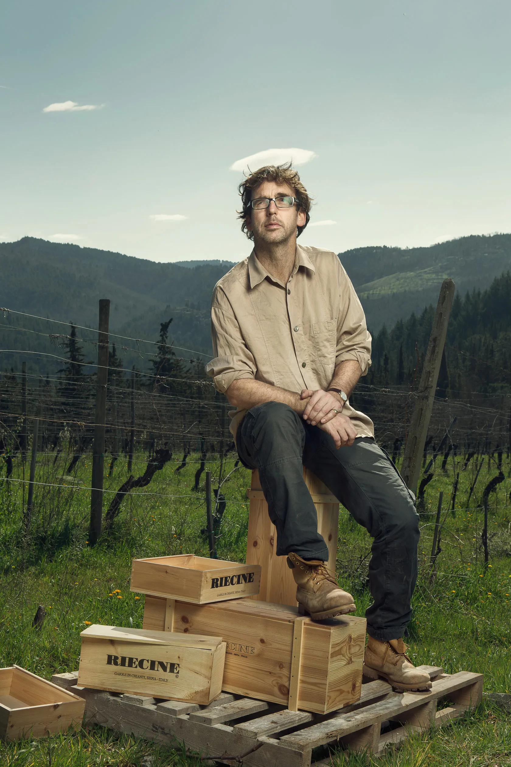 Sean O’Callaghan sits on a stack of Riecine crates in a hillside vineyard.