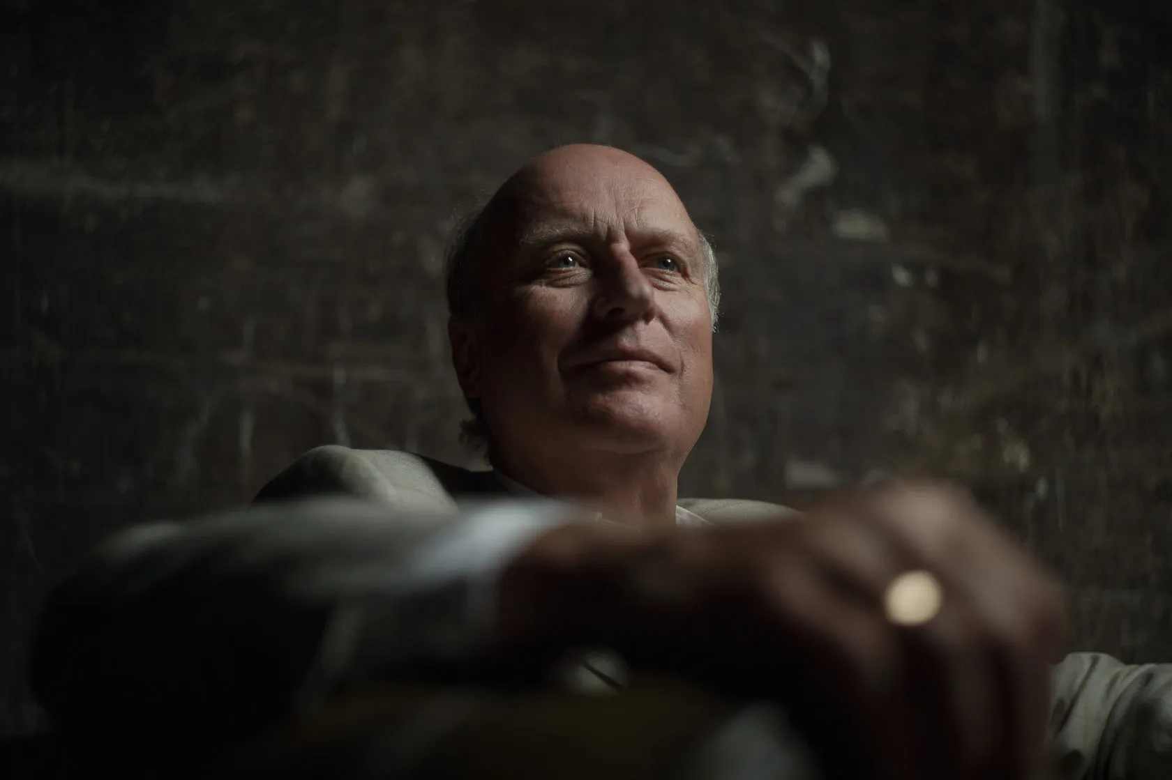 Philippe Baijot, lit from the side, rests on his arms in a dark room.